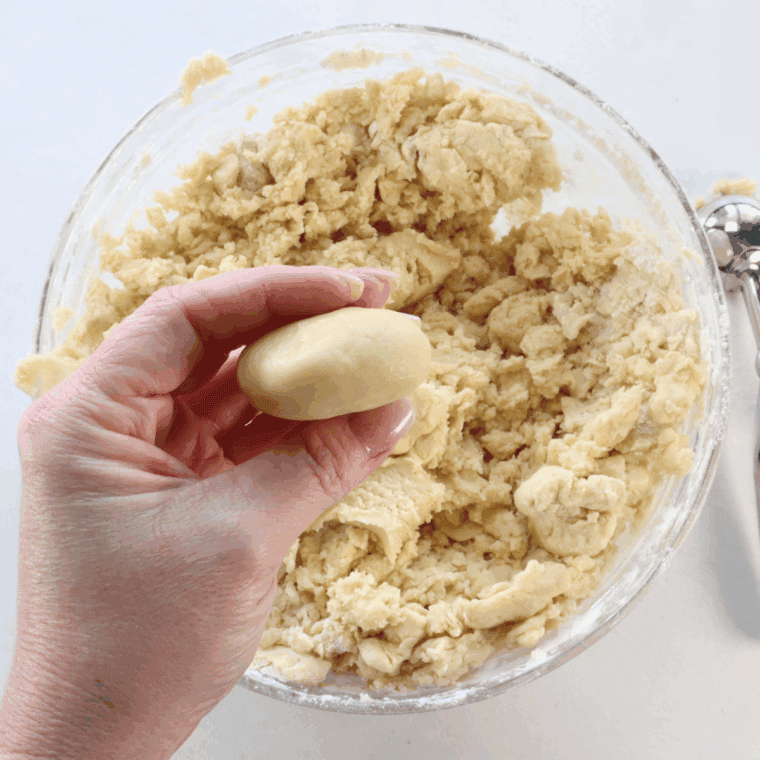 Shaping sugar cookie dough balls and flattening them slightly on a parchment-lined baking sheet