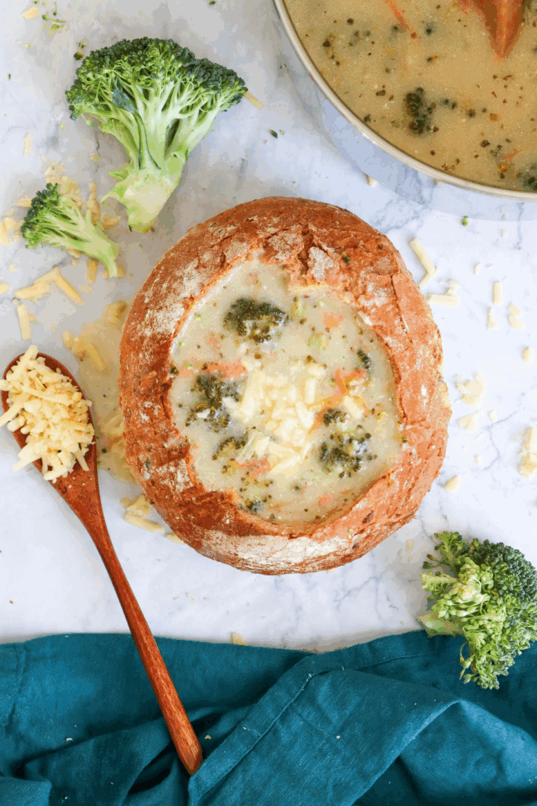 Bowl of creamy Copycat Subway Broccoli and Cheese Soup topped with melted cheddar and fresh broccoli florets.