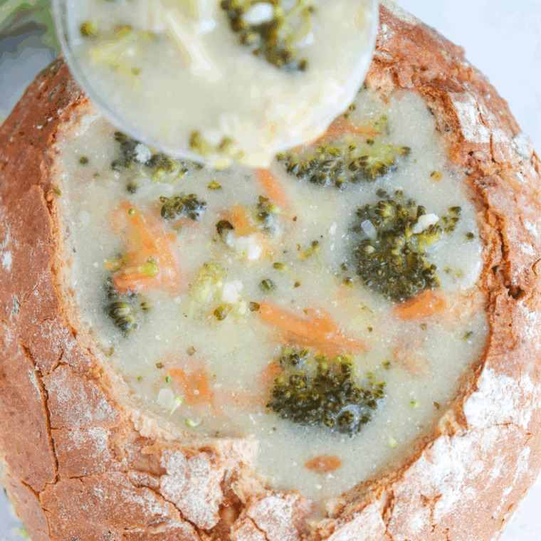 Bowl of creamy, cheesy broccoli soup, garnished with shredded cheddar.