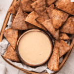 Creamy dip served in a bowl alongside crunchy cinnamon sugar pita chips.