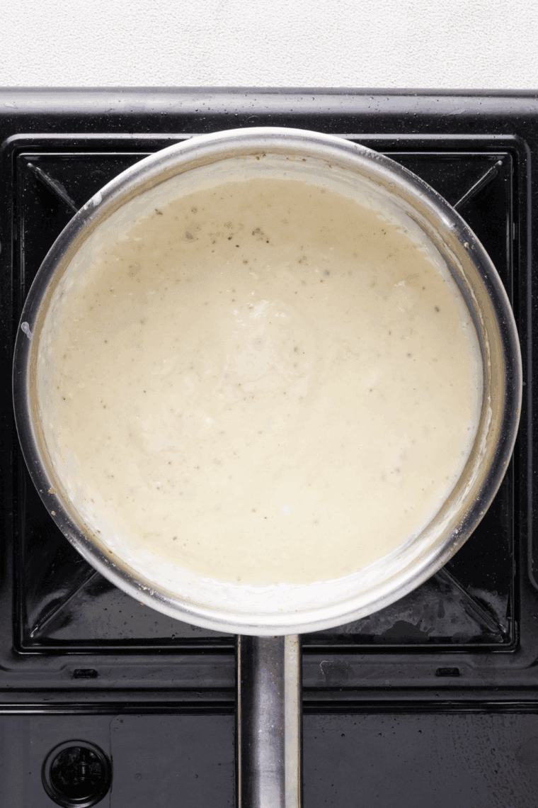 Pouring melted butter and warm heavy cream into caramelized sugar, stirring until smooth and glossy.