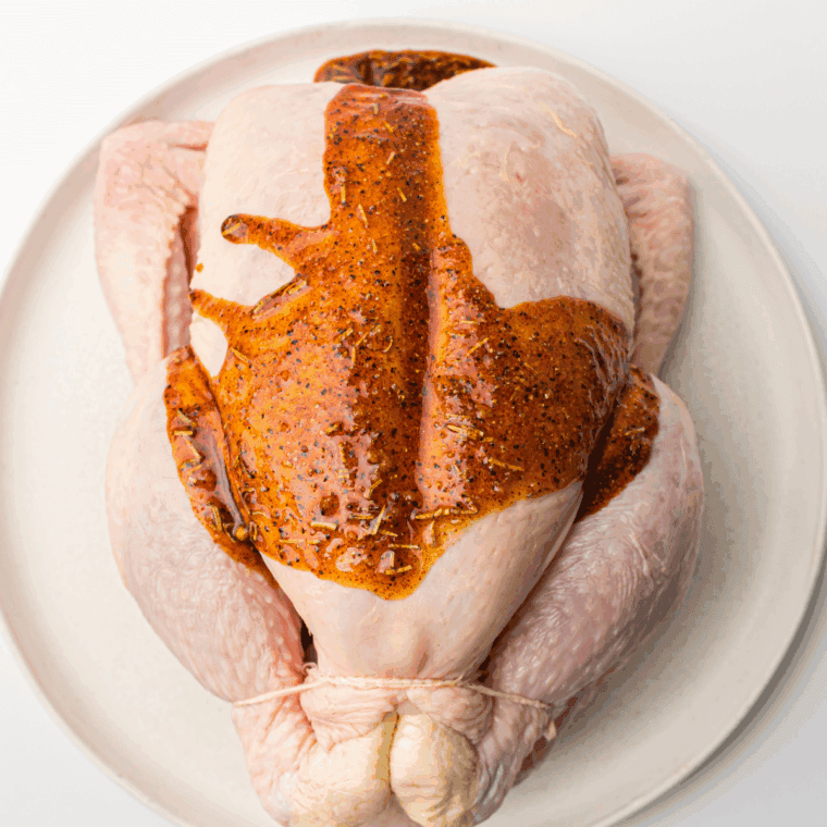 Whole raw chicken on a cutting board, patting dry with paper towels.