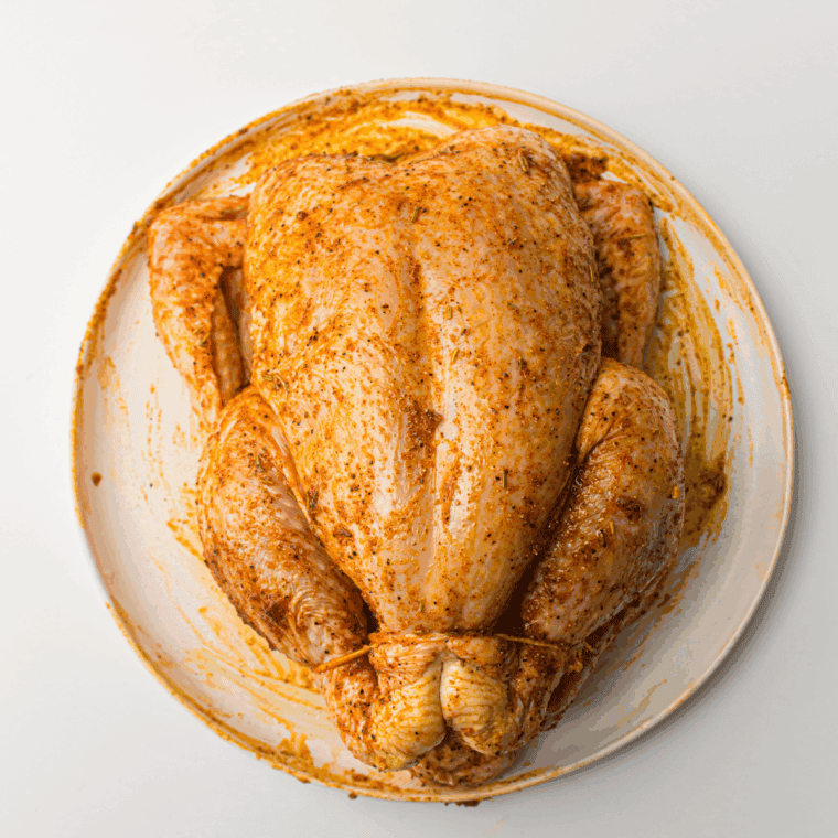 Chicken being rubbed with butter, olive oil, thyme, salt, pepper, lemon, and g