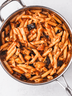 Ina Garten’s homemade marinara sauce simmering in a skillet with fresh herbs and vibrant tomatoes.