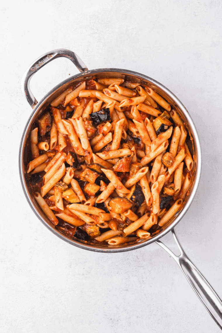 Skillet of Ina Garten’s marinara sauce with onions, garlic, and fresh herbs simmering.