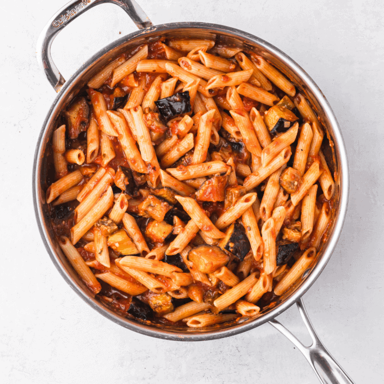 Homemade Ina Garten marinara sauce simmering in a skillet with fresh herbs and crushed tomatoes.