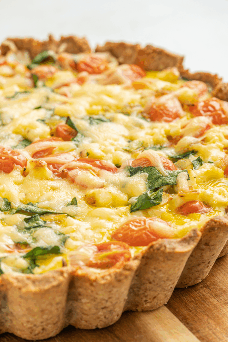 Slice of Ina Garten’s quiche with golden crust and creamy egg filling on a plate.