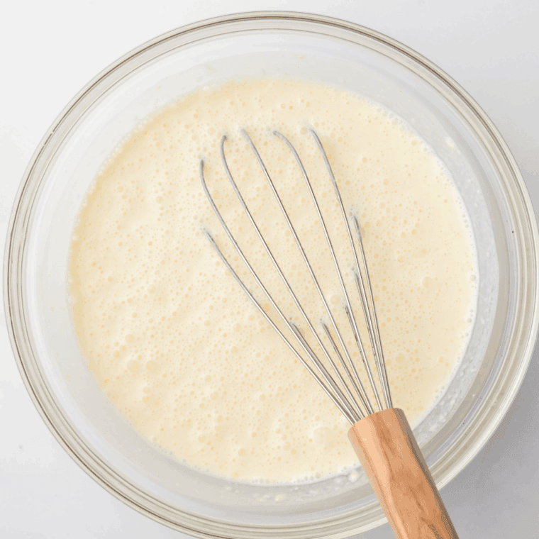 Whisking together whole milk, heavy cream, butterscotch pudding, caramel, and vanilla in a large bowl to make Butterbeer ice cream base.