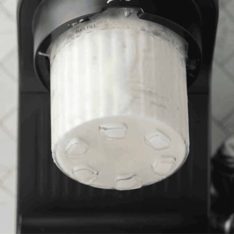 Inserting frozen pint into the Ninja Creami machine and churning into creamy ice cream.