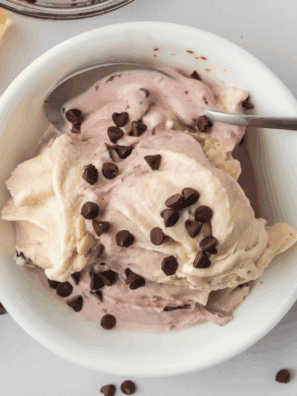 A pint of creamy Ninja Creami cherry chocolate ice cream with chocolate chunks and fresh cherries.