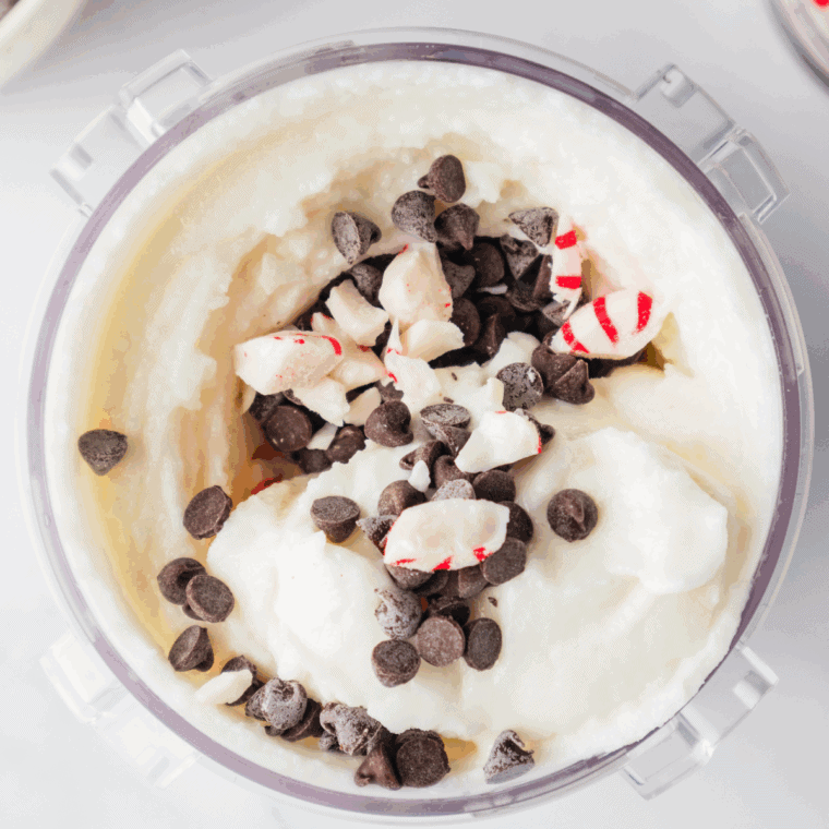Mini chocolate chips and crushed peppermint candies being mixed into ice cream.