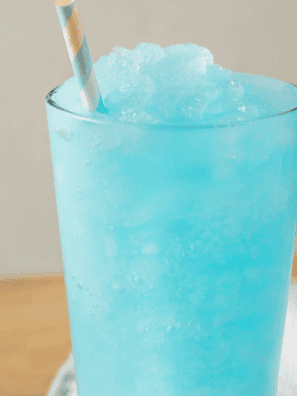 Homemade Ninja Slushi Blue Raspberry Slush in a glass with ice and garnish.