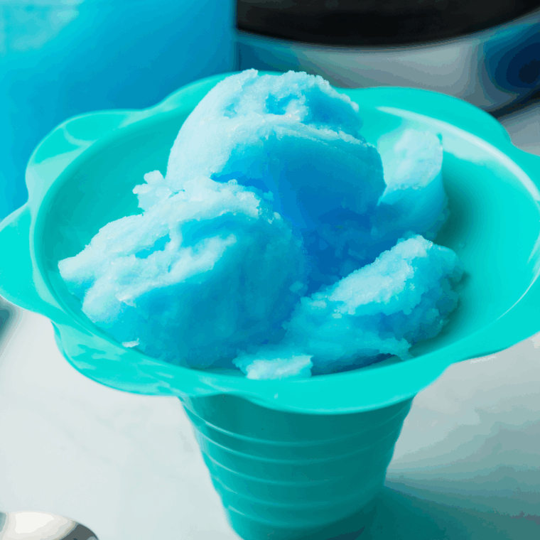 “Easy Ninja Slushi Blue Raspberry Slush in a clear glass with ice and garnish.”