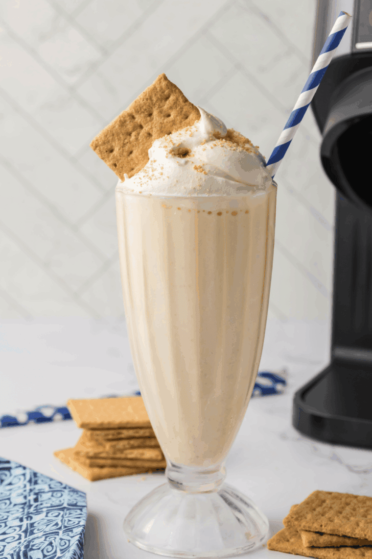 Creamy Ninja Slushi eggnog milkshake topped with whipped cream, cinnamon, and nutmeg, served in a festive glass for the holidays.