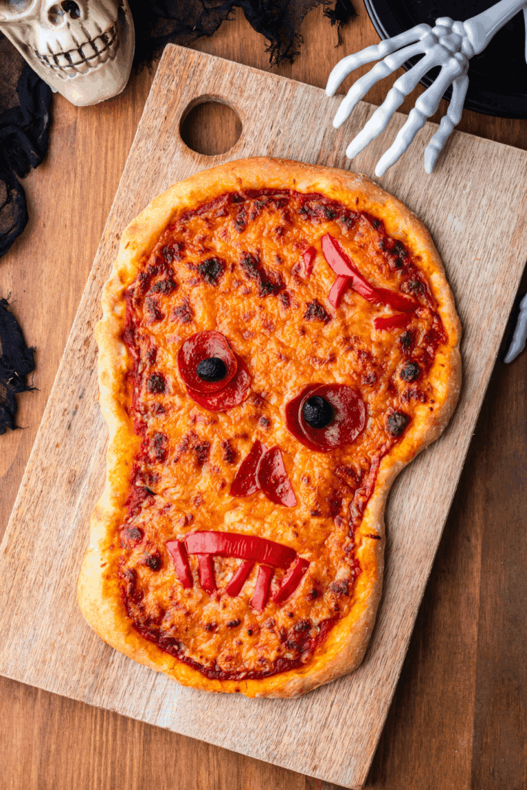 Skull-shaped Halloween pizza topped with cheese, pepperoni, and olives.