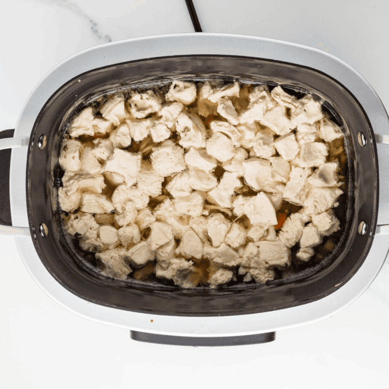 Slow cooker with chicken and vegetables simmering on low heat.