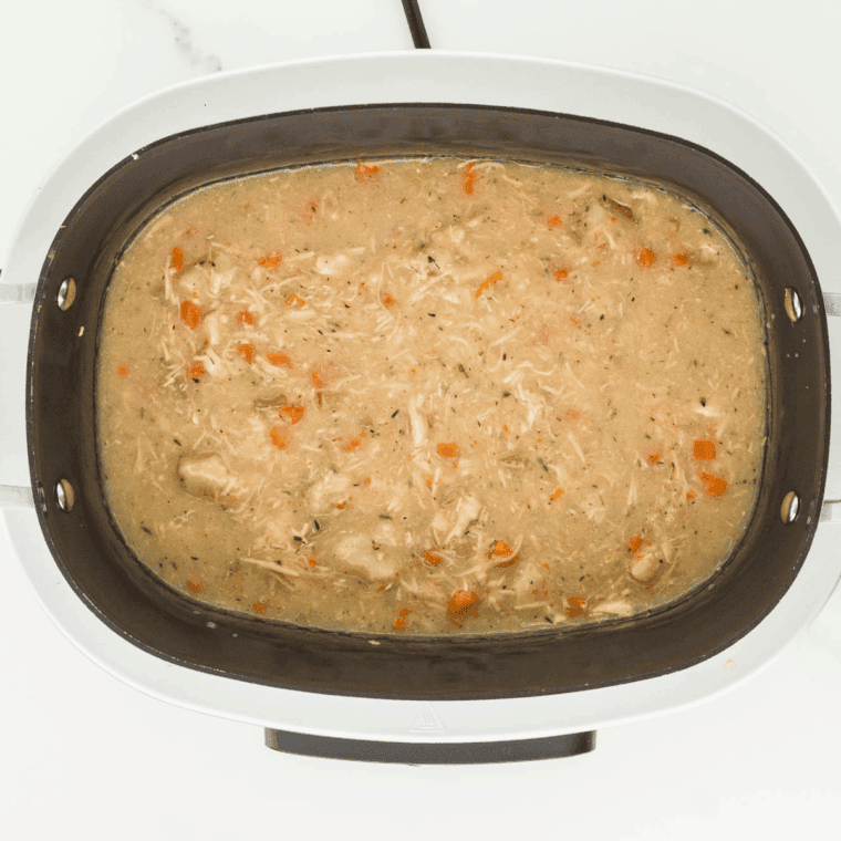 Biscuit pieces placed on top of simmering chicken and vegetable broth.