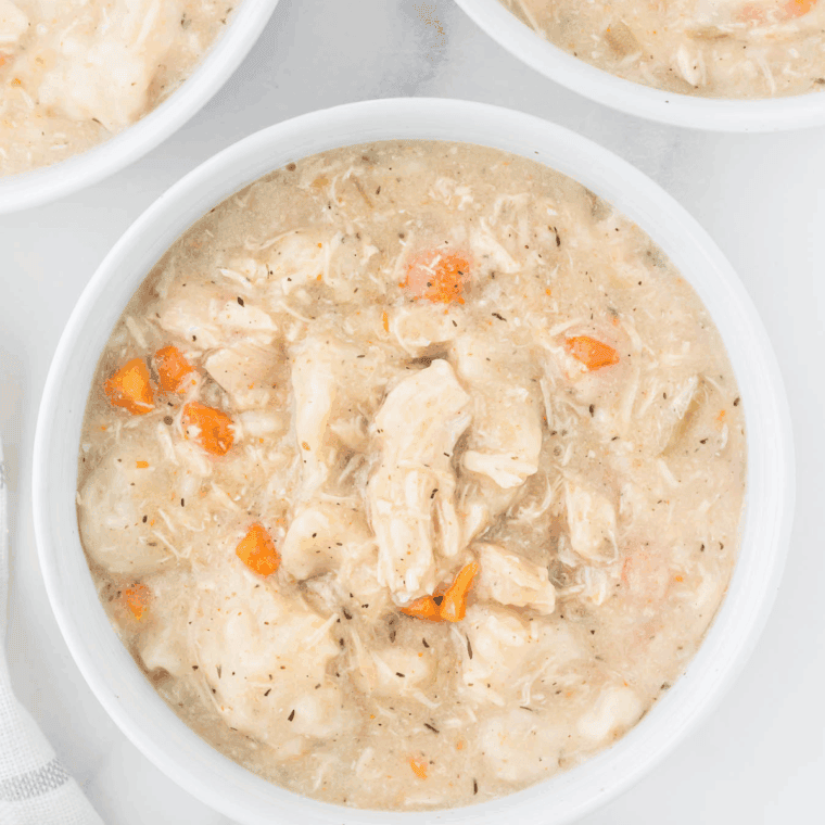 Bowl of slow cooker chicken and dumplings with tender chicken and fluffy dumplings in savory broth.