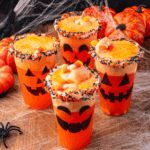 Halloween Jack-O-Lantern Floats made with orange soda and vanilla ice cream, served in pumpkin-themed glasses with festive straws.