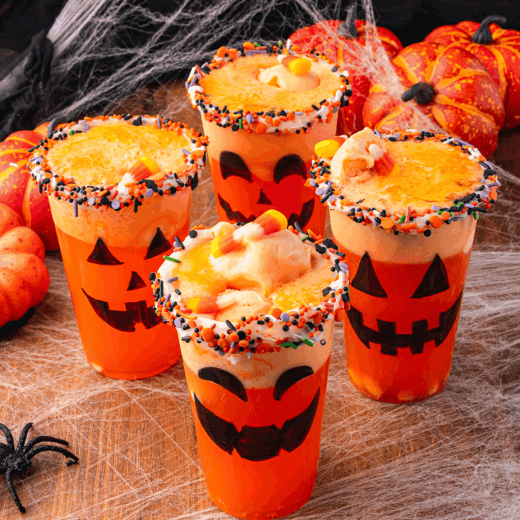 Halloween Jack-O-Lantern Floats made with orange soda and vanilla ice cream, served in pumpkin-themed glasses with festive straws.