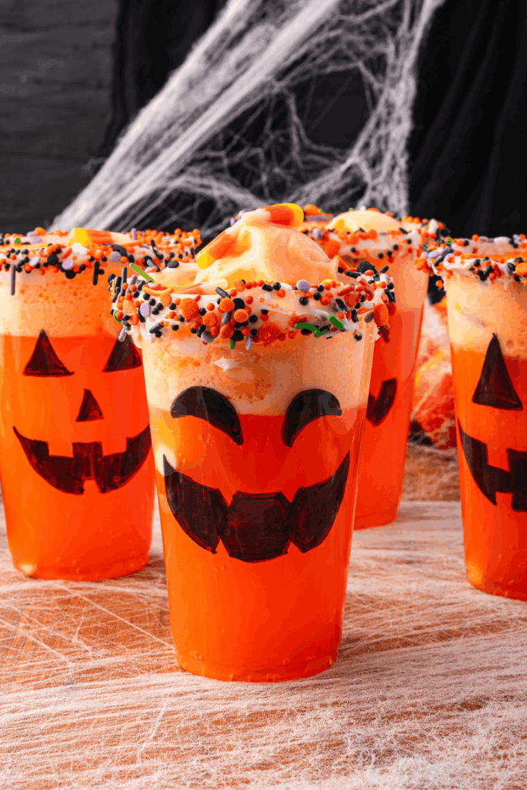 Halloween Fanta Jack O’Lantern Floats made with orange soda, sherbet, and festive sprinkles served in cups with Jack-O’-Lantern faces.