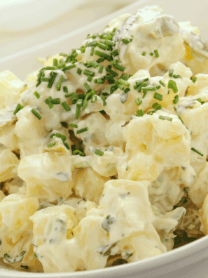 Bowl of creamy French Potato Salad by Barefoot Contessa garnished with fresh parsley and chives.