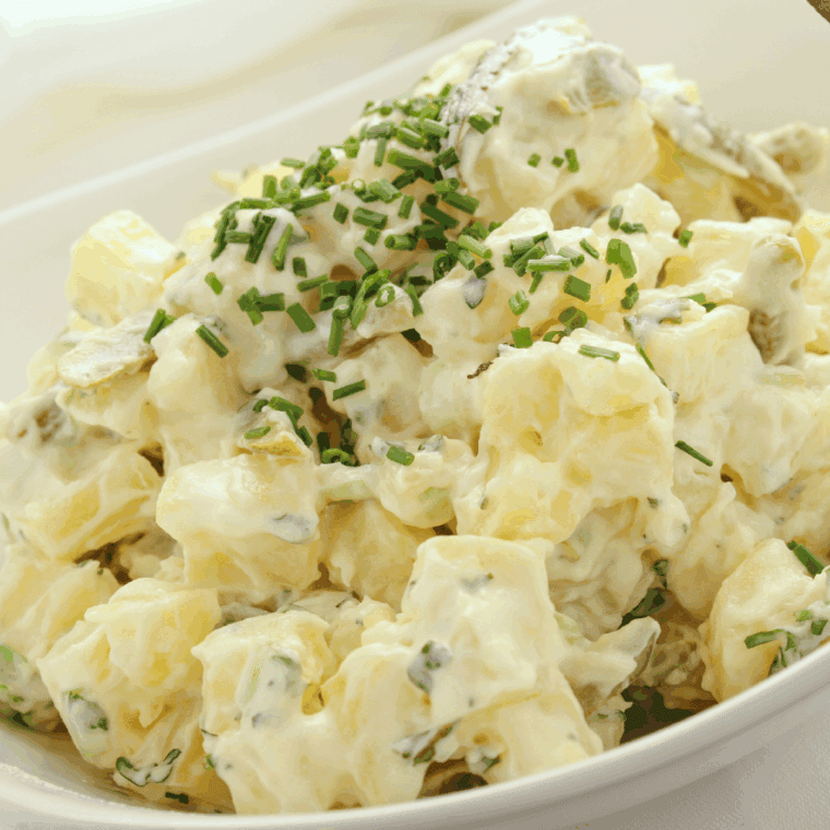 Bowl of creamy French Potato Salad by Barefoot Contessa garnished with fresh parsley and chives.