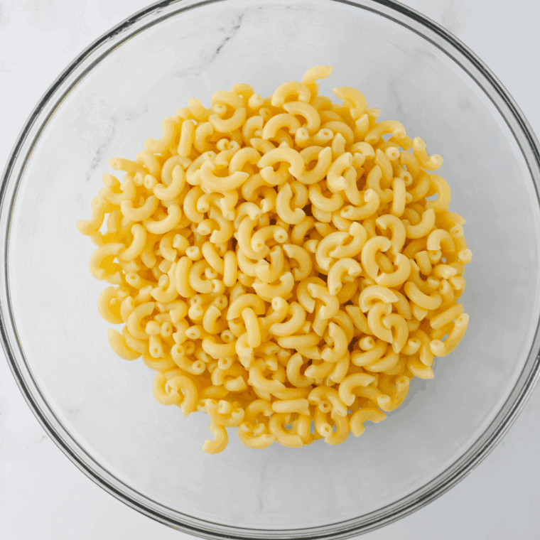 Elbow macaroni boiling in salted water, then drained and rinsed under cold water.