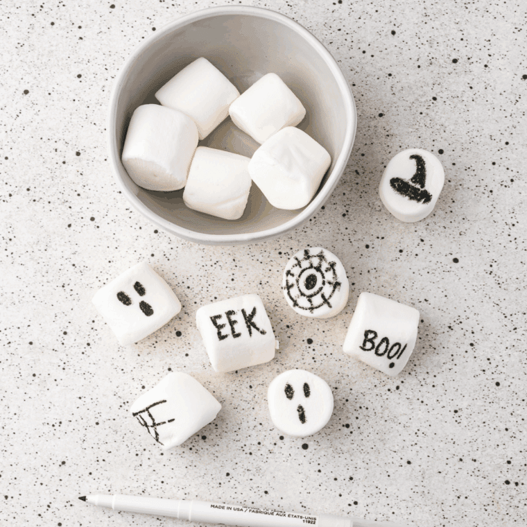 Decorating marshmallows with edible markers and placing them on whipped cream mounds.