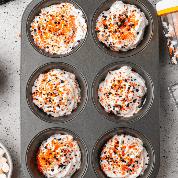 Sprinkling Halloween-themed decorations on whipped cream mounds before freezing until firm.