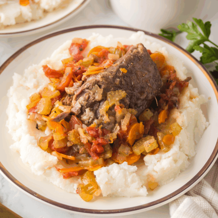 Golden-brown veal shank braised in white wine sauce with carrots, celery, and herbs, served over creamy risotto.