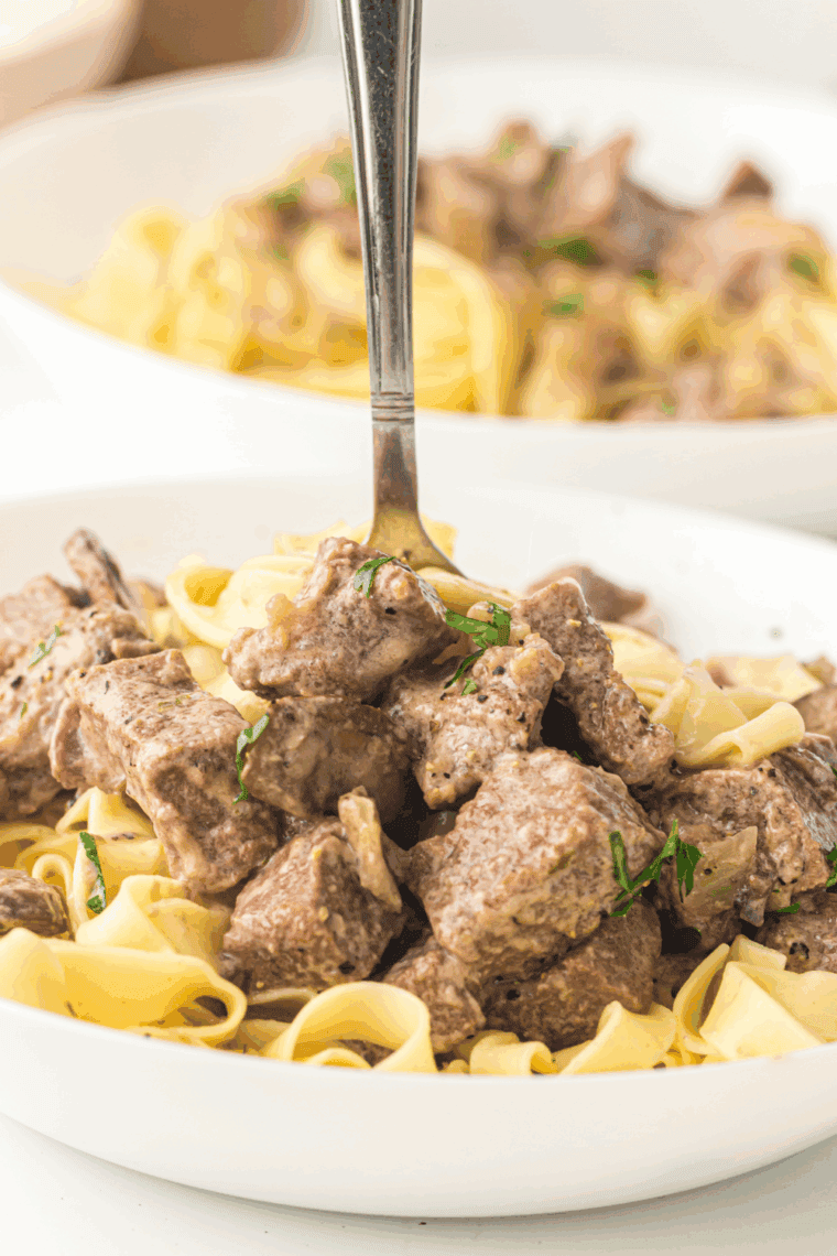 Ina Garten's Beef Stroganoff on white plate with a fork on top.