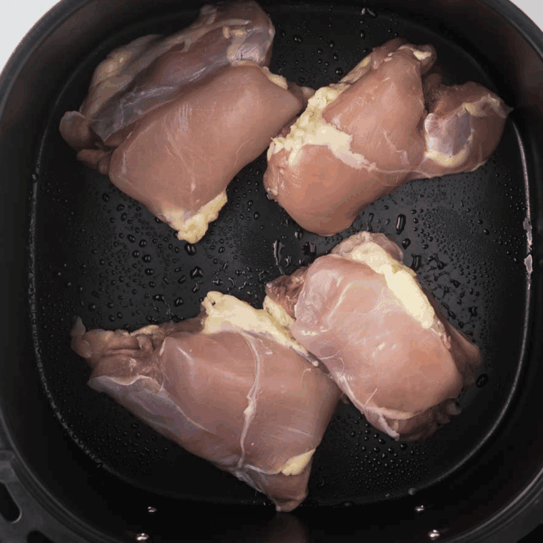 Seasoned chicken thighs being browned in a skillet with olive oil until golden on both sides.