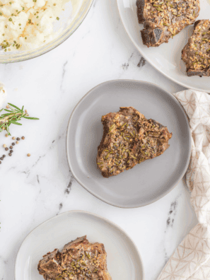 Grilled Moroccan lamb chops on a plate, garnished with fresh herbs and lemon wedges.