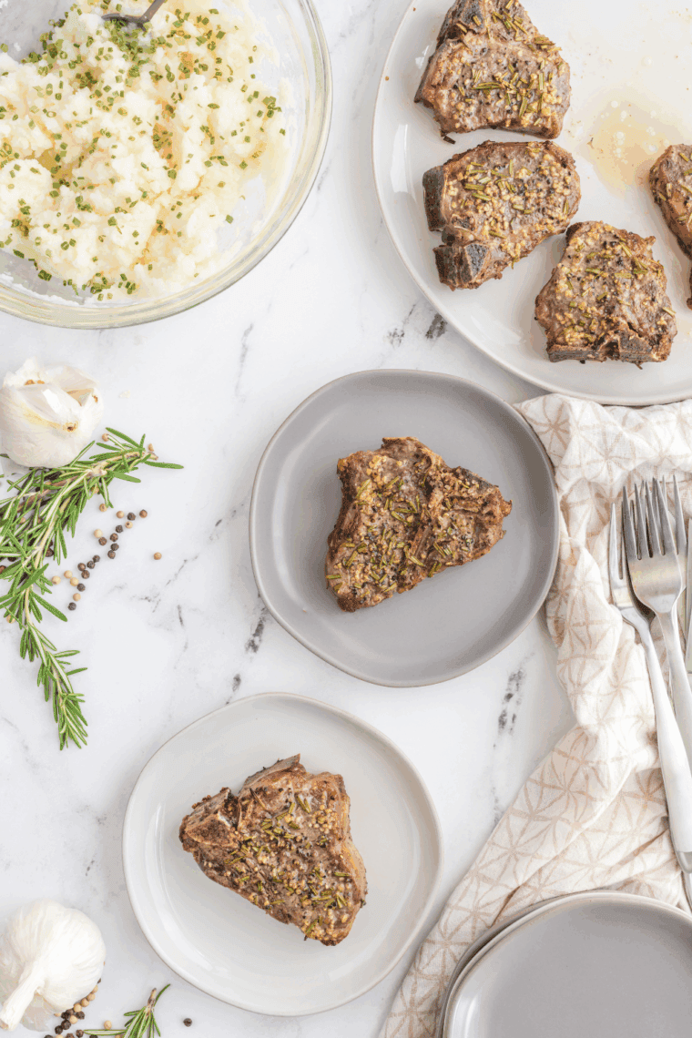 Grilled Moroccan lamb chops garnished with fresh herbs and lemon wedges on a plate.