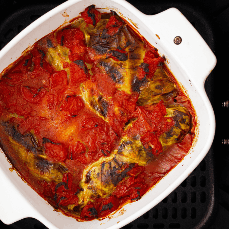 Plate of Ina Garten’s stuffed cabbage rolls filled with beef and rice, topped with tomato sauce and garnished with fresh parsley.