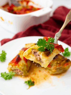 Plate of Ina Garten’s Stuffed Cabbage Rolls topped with rich tomato sauce and fresh herbs.