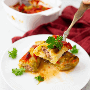 Plate of Ina Garten’s Stuffed Cabbage Rolls topped with rich tomato sauce and fresh herbs.