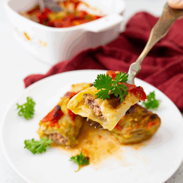 Plate of Ina Garten’s Stuffed Cabbage Rolls topped with rich tomato sauce and fresh herbs.