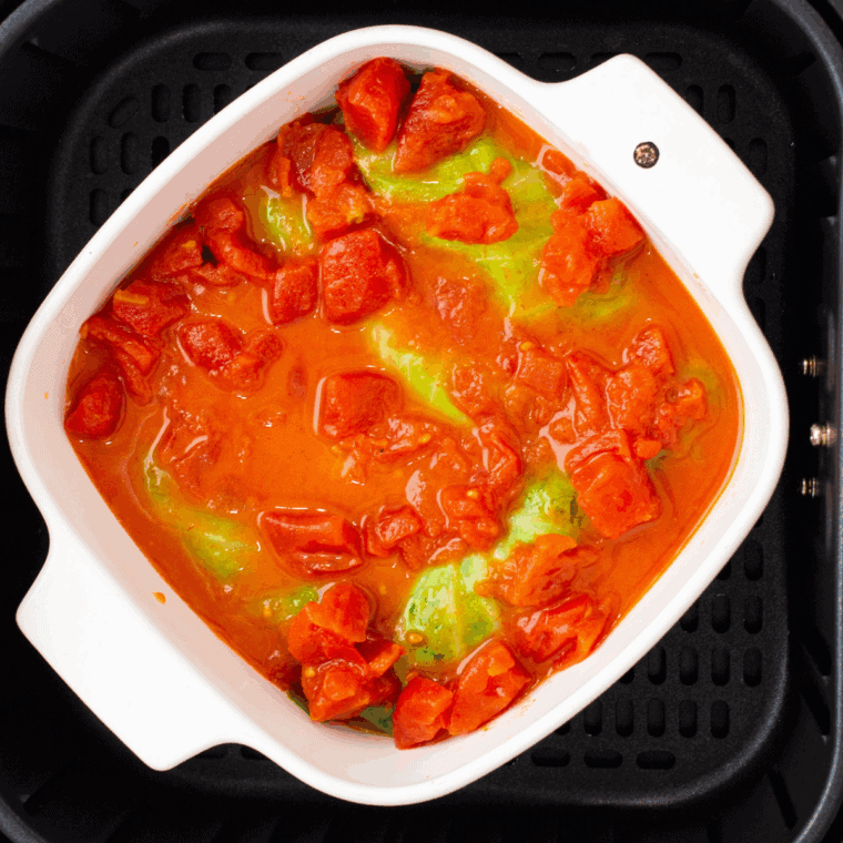 Layering stuffed cabbage rolls in a baking dish and covering them evenly with tomato sauce.