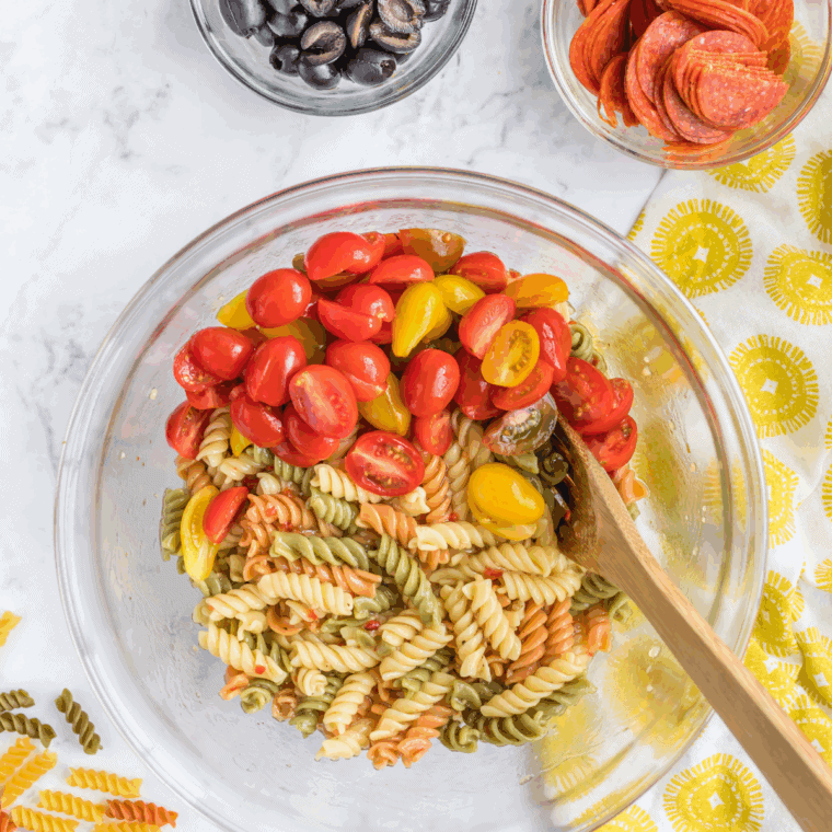 Boiling rotini pasta in a pot until al dente, then draining and rinsing under cold water.