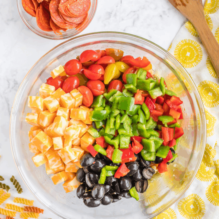 Folding the cooled pasta into the creamy dressing and vegetable mixture until evenly coated.