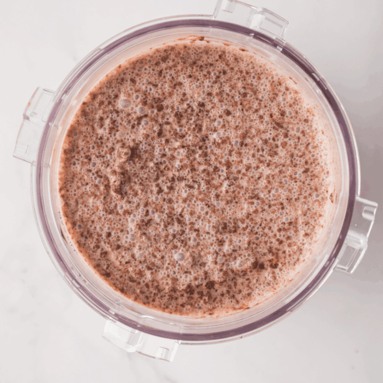Pouring chocolate ice cream mixture into a Ninja Creami pint container and freezing until solid.