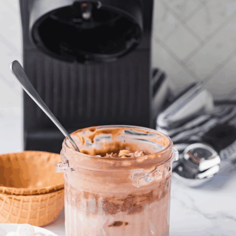 Processing the ice cream in the Ninja Creami to evenly fold in marshmallows, almonds, and chocolate chunks.