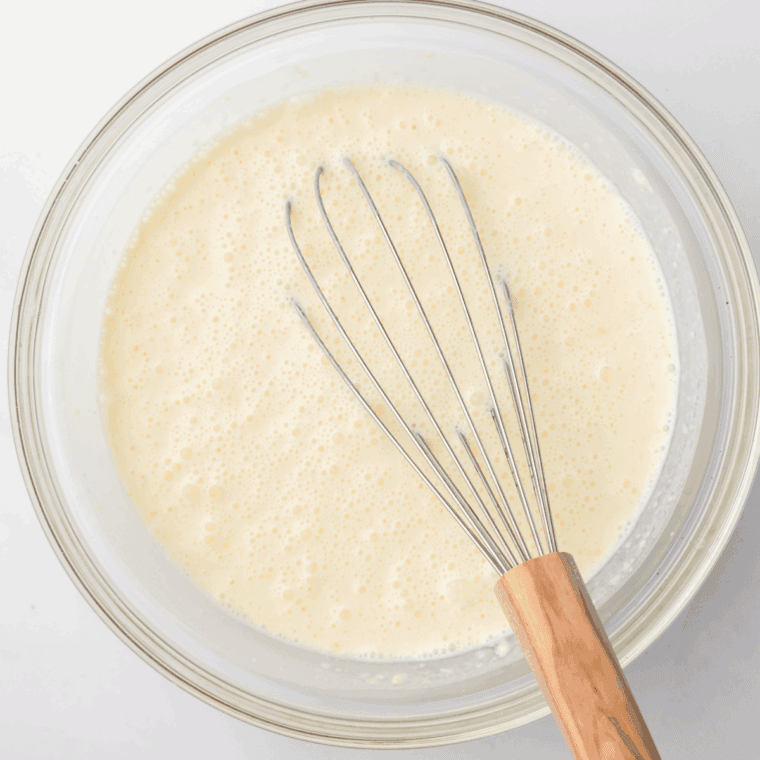 Blender with bananas, cream, chocolate syrup, and condensed milk being blended smooth.