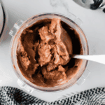 Scoops of creamy chocolate malt ice cream served in a bowl, topped with chocolate syrup and malted milk balls.