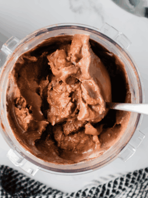 Scoops of creamy chocolate malt ice cream served in a bowl, topped with chocolate syrup and malted milk balls.