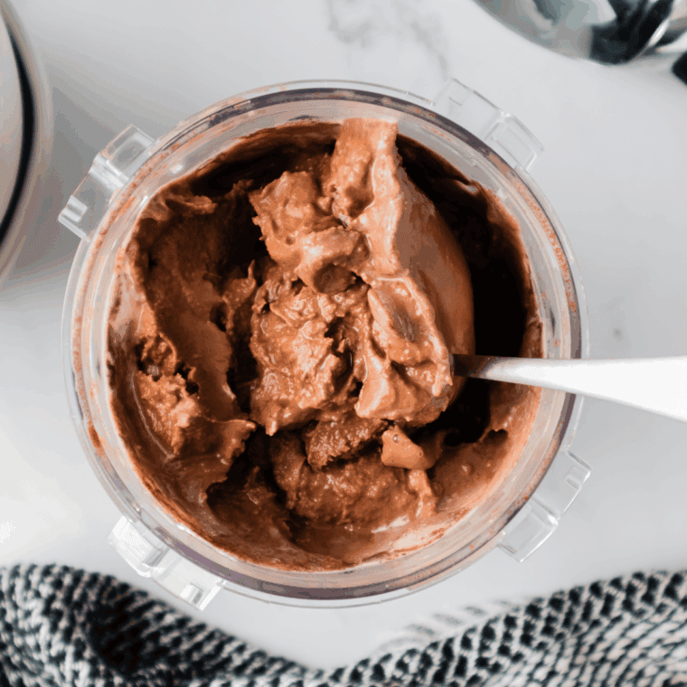 Scoops of creamy chocolate malt ice cream served in a bowl, topped with chocolate syrup and malted milk balls.