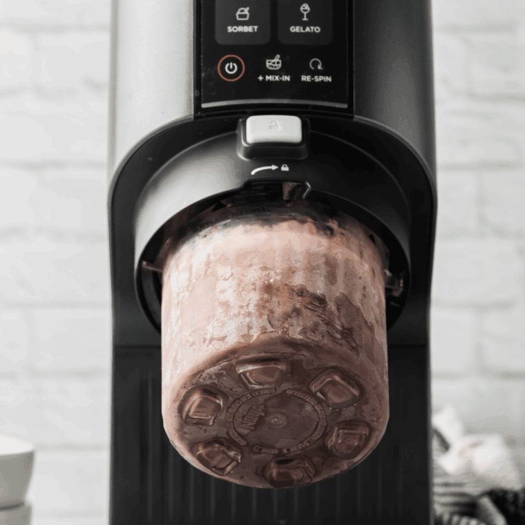 Frozen pint container placed in the Ninja Creami machine for processing into ice cream.