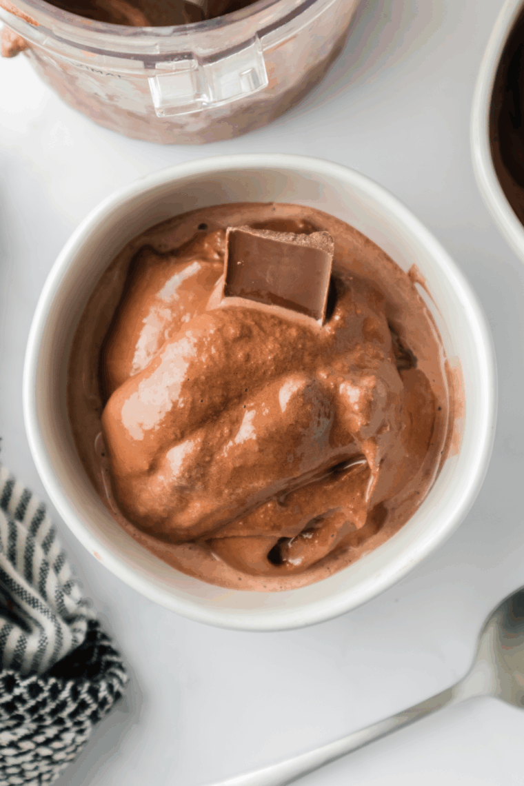 Bowl of creamy chocolate malt ice cream made in the Ninja Creami, topped with chocolate syrup and malted milk balls.